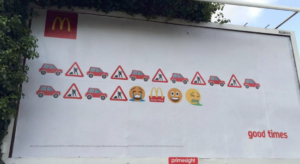 A McDonald's billboard with a story about being stuck in traffic, then grabbing a Big Mac and being happy. A graffiti artist adding a barfing face emoji to the end.