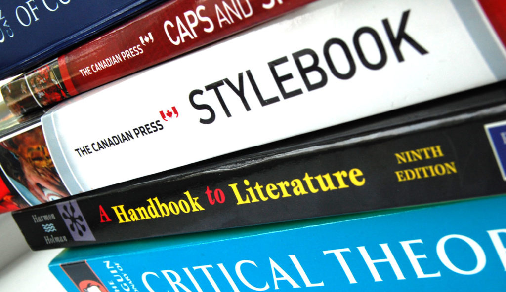 A stack of books about language and writing guidelines (The Canadian Press stylebook, Canadian Press Caps and Spelling, A Handbook to Literature and Penguin's Critical Theory