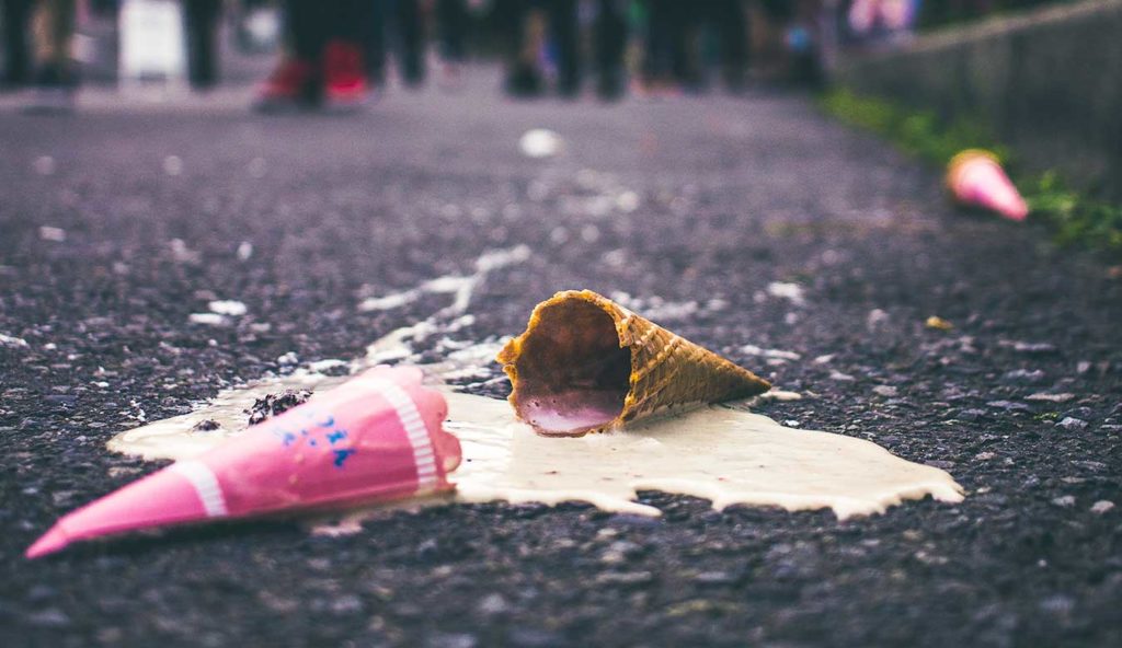 An ice cream cone, spilled and melted on a road.